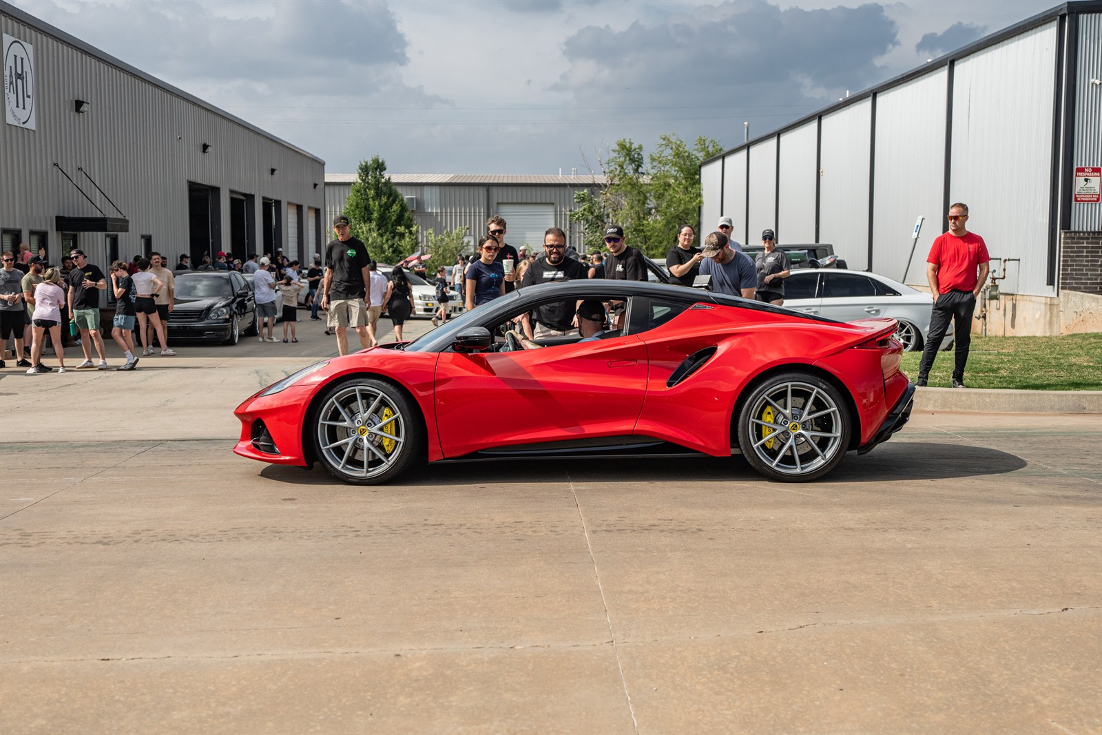 Diego Siverio drives his red Lotus Emira while talking to someone before turning in to park at the memorial meet.