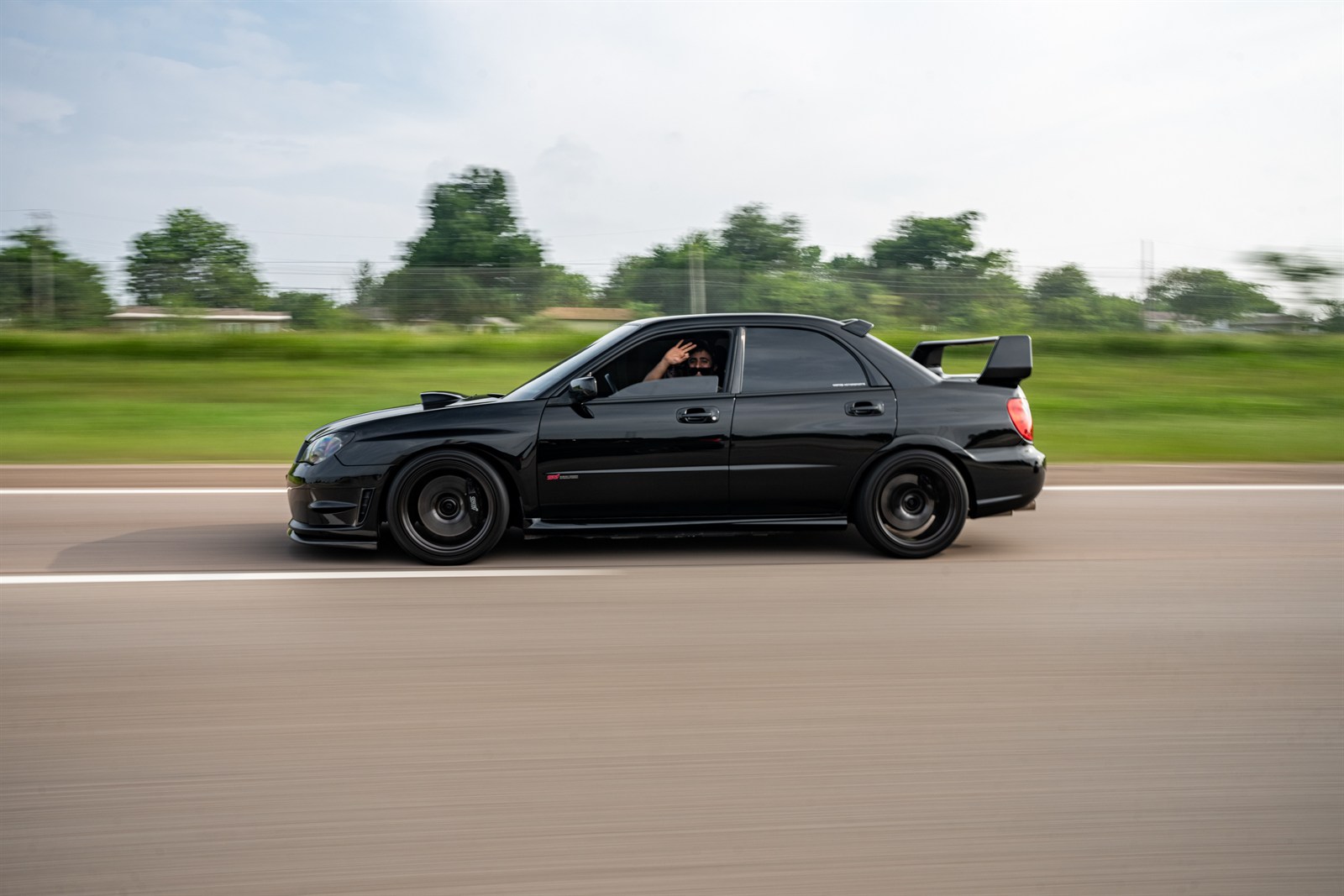 Shawn Abedi waves from a black Subaru during the memorial cruise.